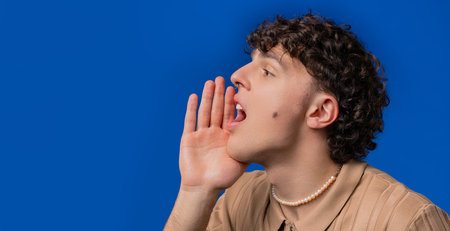 Portrait Of Handsome Man Shouting, Holding Hand Near Open Mouthの写真素材