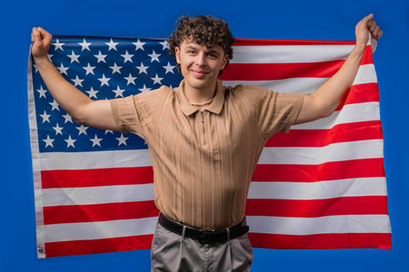 Happy handsome man with national USA flag on blue background. American patriotの写真素材