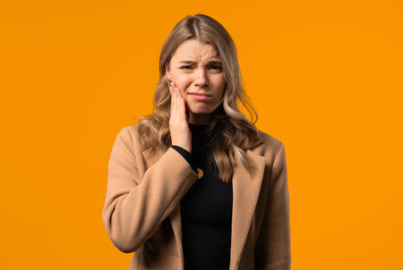 Young businesswoman with tooth pain, yellow background.Toothache, dental problemの写真素材