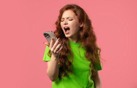 Woman quarreling while talking on mobile phone. Angry, stress on Pink. Conflictの写真素材