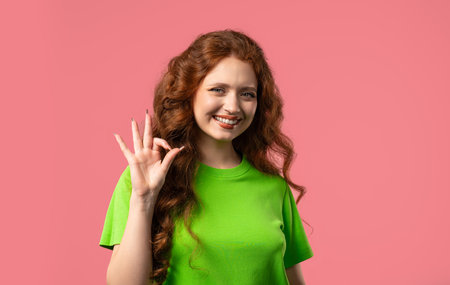 Pretty woman makes hand sign okay, ok gesture. Happy girl,correct perfect choiceの写真素材