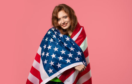 Smiling woman with national USA flag on pink background. American patriot
