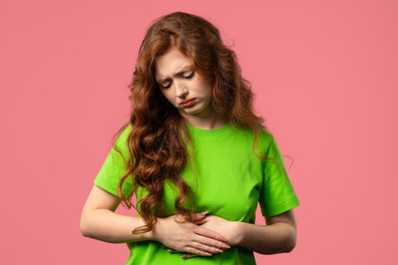Young woman squeezing belly with hands. abdominal pain, suffering stomach acheの写真素材