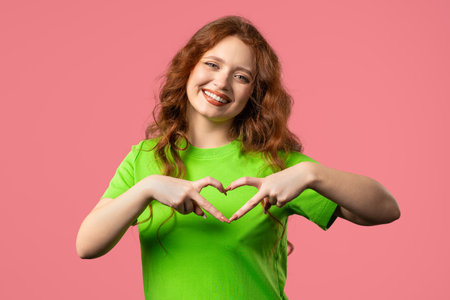 Smiling woman showing sign of shape heart. Positive lady on pink. Love. healthの写真素材