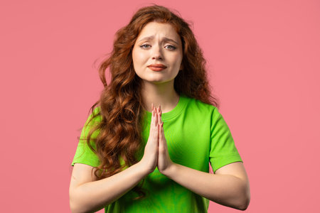 Woman praying, begs to apologize, she guilty. pink background. Hopeful prayer.
