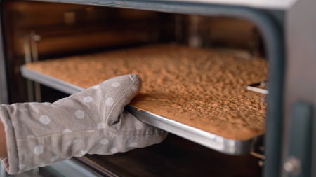 Pastry chef takes out baking sheet with finished cake layer from oven. Dessertの写真素材