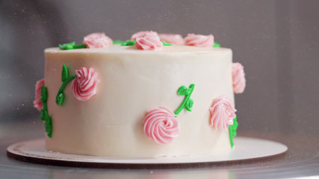 Elegant cake on turntable.Pink buttercream flowers on frosting. Bakery, pastryの写真素材