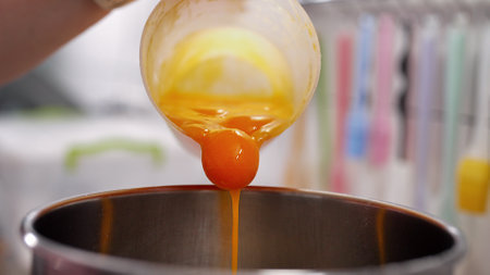 Yellow yolks are added in metal stand mixer bowl. Whipping eggs for bakingの写真素材