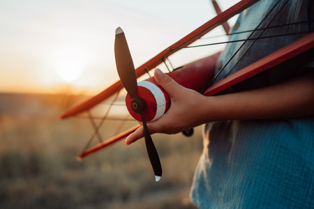 Close-up hands of child Boy holds Craft Wooden Retro Styled Airplane. Travelingの写真素材