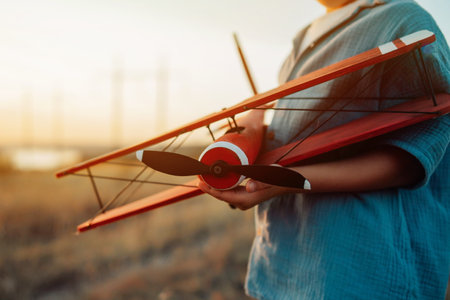 Close-up hands of child Boy holds Craft Wooden Retro Styled Airplane. Travelingの写真素材