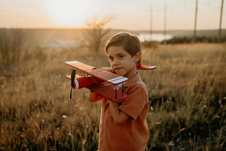 Smiling preschool child boy plays with craft wooden retro styled airplaneの写真素材