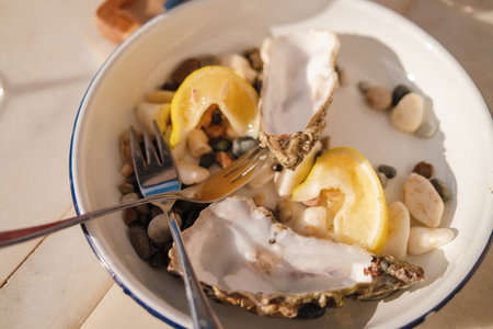 Fresh oysters on ceramic plate with lemon wedges served for gourmet dining