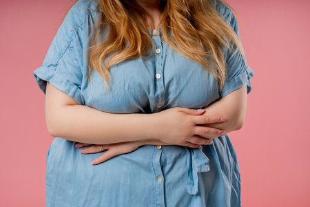 Plus Size Woman Squeezing Belly With Hands. Abdominal Pain, Suffering Stomach