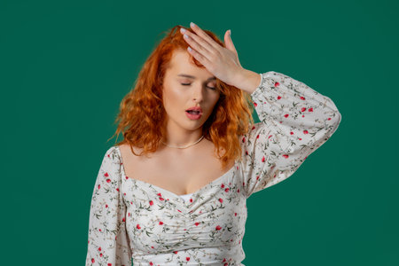Frustrated red-haired woman sighs, facepalms after unexpected reaction, forgotの写真素材