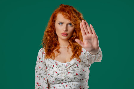 Ginger woman with open palm in stop gesture, clear assertive body languageの写真素材