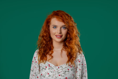 Headshot of kind smiling auburn woman with natural curly hair, joyful expressionの写真素材