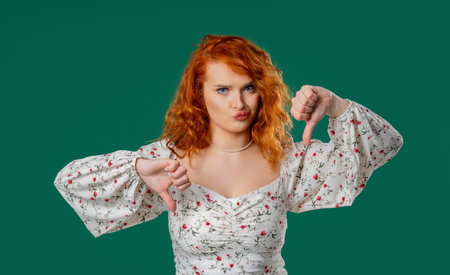 Ginger Woman With Dislike. Grimacing Condemning Curly Lady Shows Thumbs-Downの写真素材