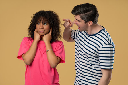 Grumpy man scolds on african american woman. Irritated girlfriend covered ears