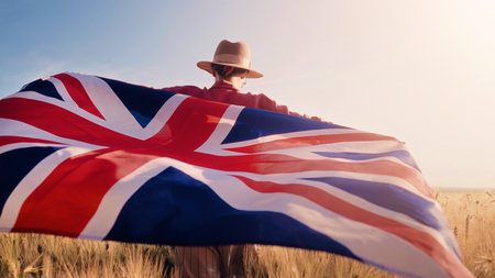 Patriot Woman Standing in Wheat Field Holding British Flag in Wind