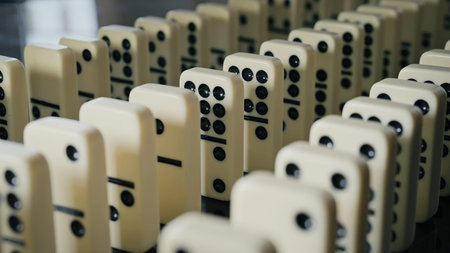 Falling domino pieces trigger a continuous chain reaction. Symbol of cause and effect