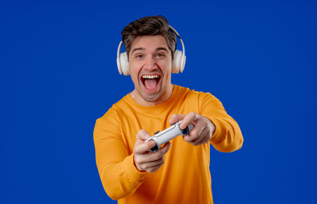 Excited Gamer Man Playing Online Video Game On Console With Gamepad On Blue