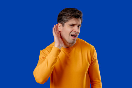 Mature Man Pointing To Ear With Confused Face, Signaling He Cant Hear Clearly