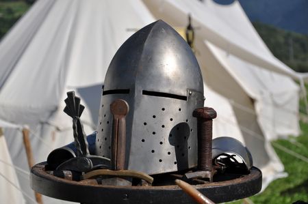 A helmet as worn by a medieval knight in middle Europe. Medieval-style tent in the background. の写真素材