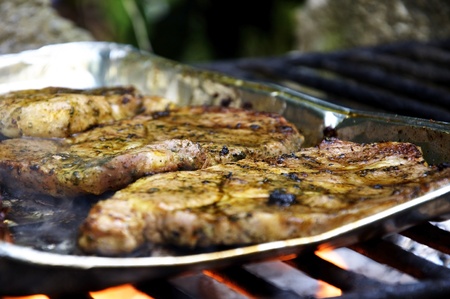 Marinated steaks being grilled on a coal grill