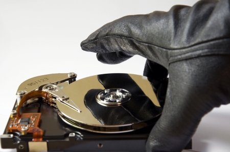 Depiction of the concept of data theft, opened harddisk and gloved hand, stealing informationのeditorial素材
