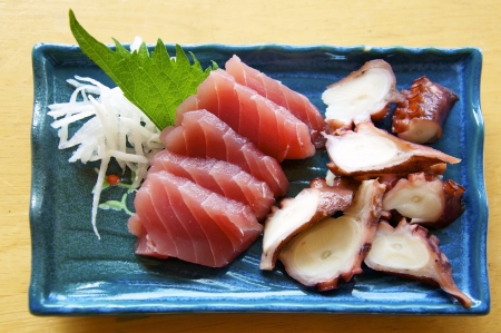 Sashimi is sliced raw fish, a traditional Japanese dish. This is tuna (maguro) and octopus (tako) with a leaf of Shiso and a little radish. の写真素材