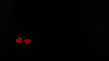 Shot from above of two small red hearts on a black background. Perspective. Valentine's Day. A lot of free space.の写真素材