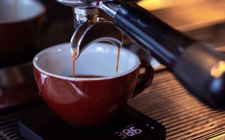 Coffee pouring from the machine through the portafilter into the cup.の写真素材