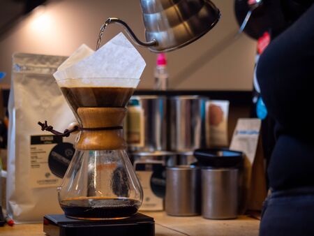 Making drip coffee. Barista pours hot water, fresh ground coffee into the paper filter.