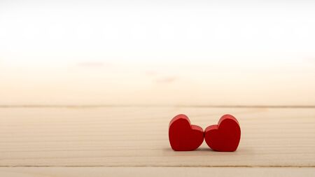 Two red hearts on a wooden table.
