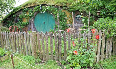 Hobbit house with red dahlia flowers - Hobbiton movie set made for "Lord of the ring" and "Hobbit" movies, Matamata,  New Zealand, 1/18/2017のeditorial素材