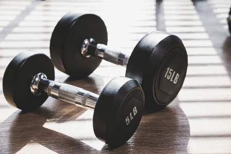 Dumbbell set indoor on brown wood floor with hard shadow from large window