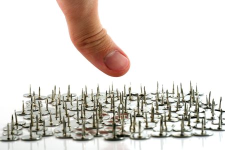 finger above thumb tacks - drawing pins, isolated on whiteの写真素材