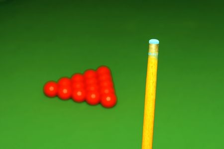 Cue stick and snooker balls over green surface, shallow depth of field
