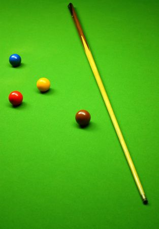 Cue stick and snooker balls over green surface, shallow depth of field