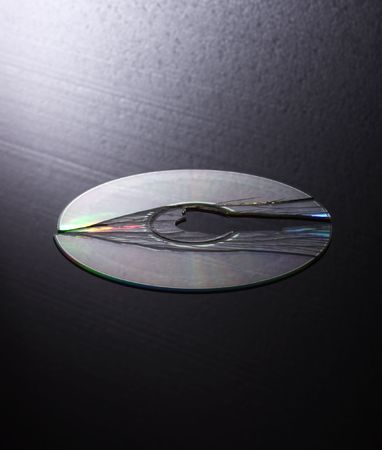 broken cd /dvd on gradient black white textured backgroundの写真素材
