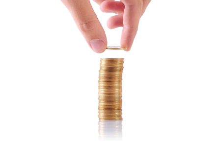 hand adding a coin to a stack of coinsの写真素材