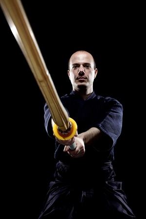 portrait of a kendo fighter with shinai, against black backgroungの写真素材
