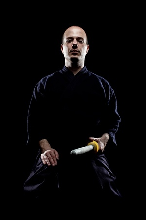 portrait of a kendo fighter with shinai, against black backgroungの写真素材