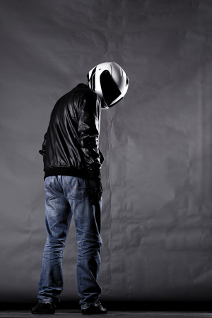 motorist with a helmet, leather jacket and jeans, on gray backgroundの写真素材
