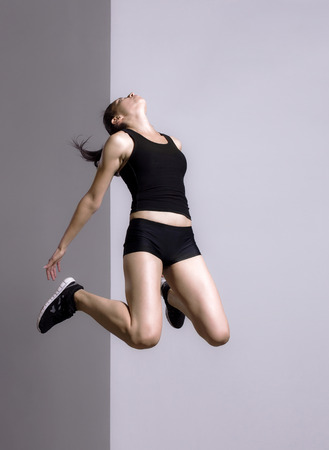 fitness girl jumping against gray backgroundの写真素材
