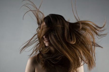 brunette girl with windy hair looking on her rightの写真素材