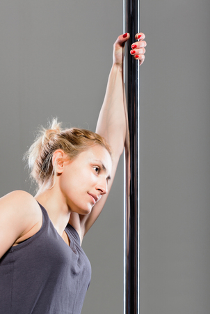 pole dance girl exercising and posing against gray backgroundの写真素材