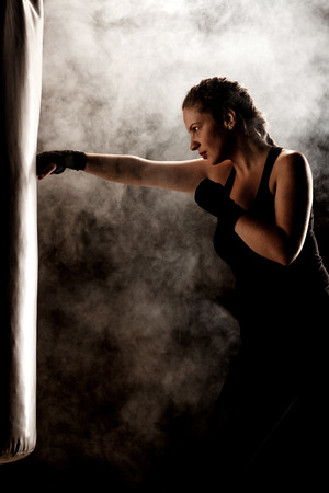 kick fighter girl punching a boxing bagの写真素材