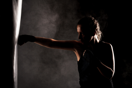 kick fighter girl punching a boxing bagの写真素材