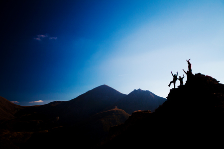 silhouette group of happy hikers on a rockの写真素材